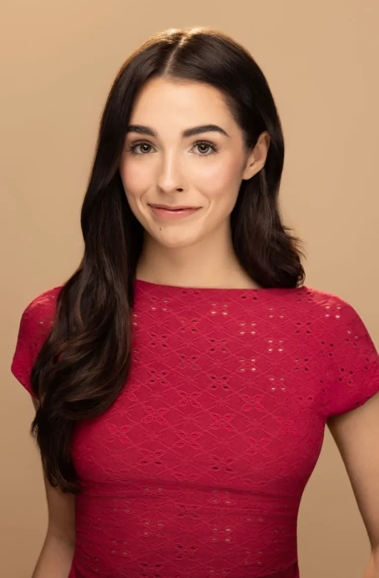 Elisabeth Fitzgerald, headshot in a red knit top on a warm beige backdrop, smiling