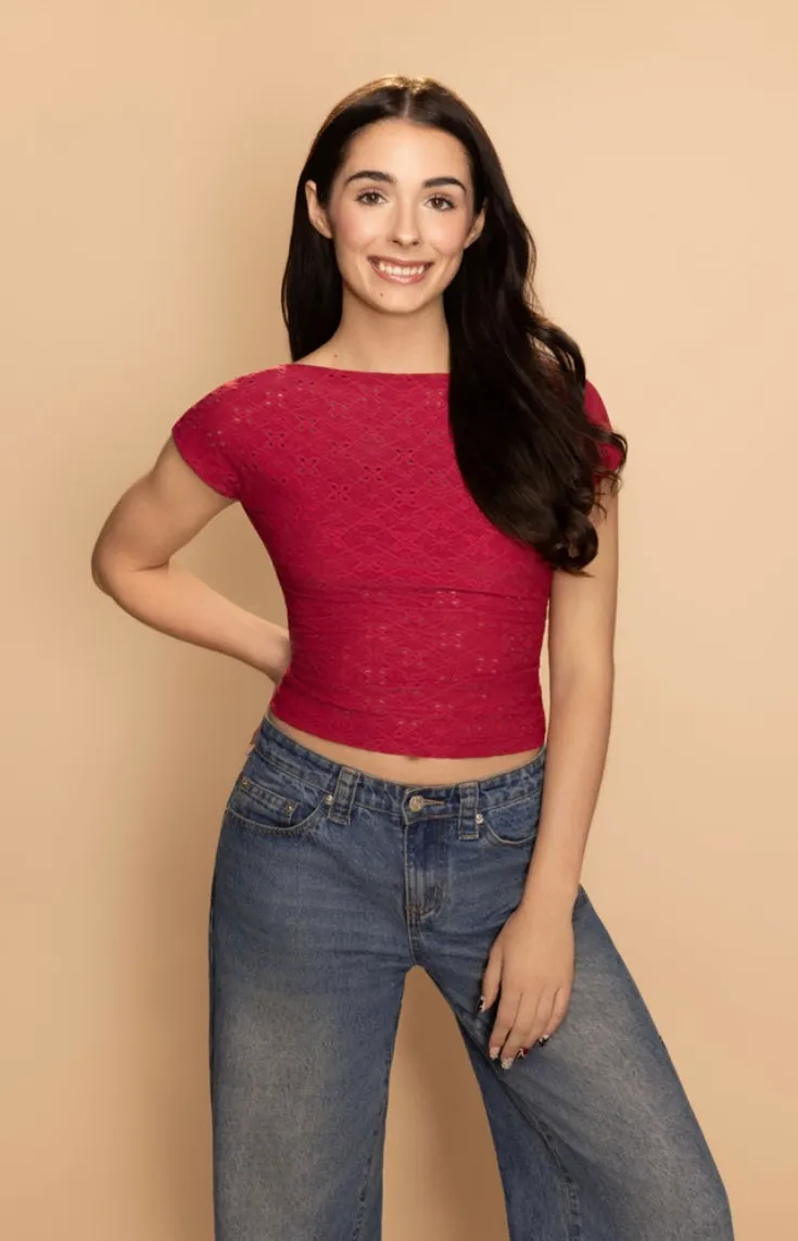 Elisabeth Fitzgerald, three-quarter length in a red top and jeans, hand on her hip, smiling broadly