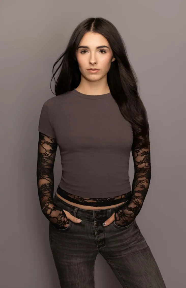 Elisabeth Fitzgerald, three-quarter length in a charcoal top with lace sleeves, hands in her pockets
